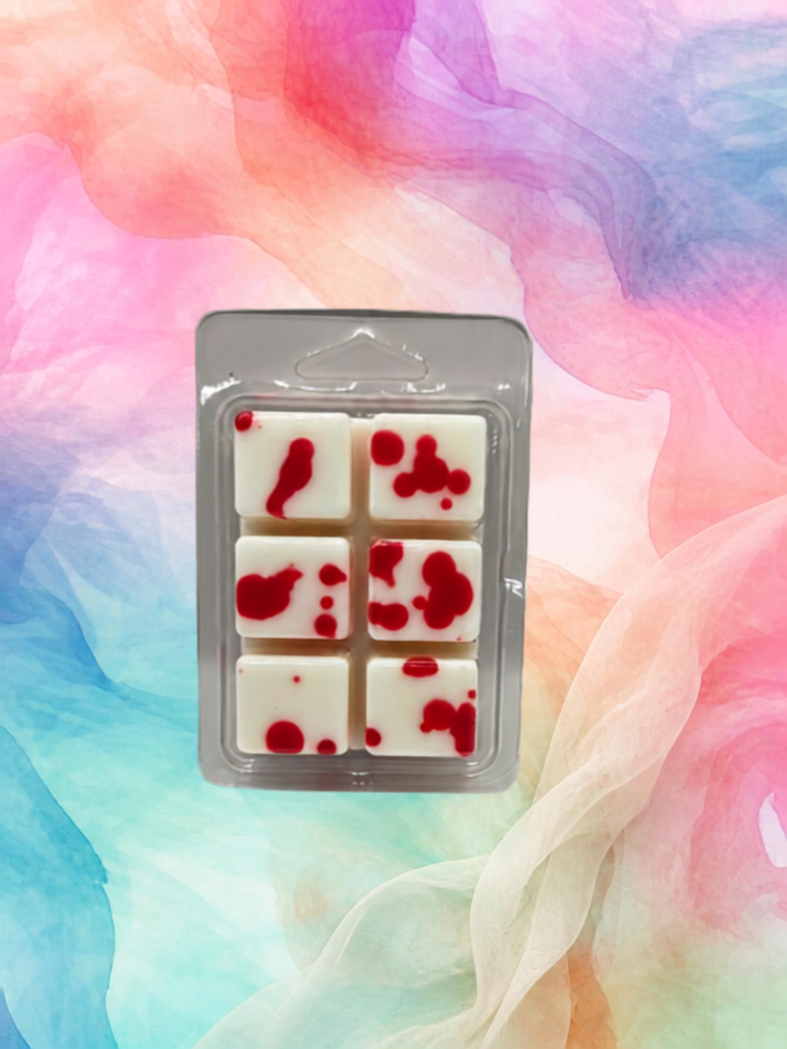 Six white wax melts with red splatter details, packaged in a clear blister pack, set against a colorful pastel watercolor background.